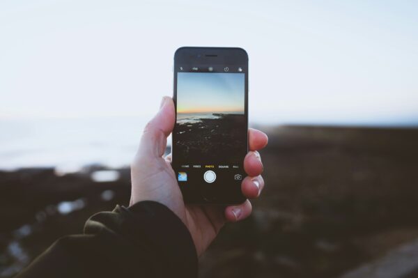 iphone on a hand taking a photo on a landscape with sea and beach in winter