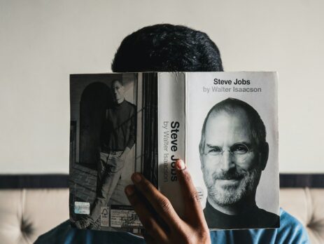 guy reading a book about steve jobs, there is a picture of him on the book cover